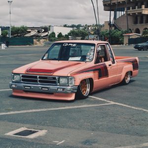 Pink Toyota pickup with copper-toned Klutch K3020 wheels, viewed from the front three-quarter angle