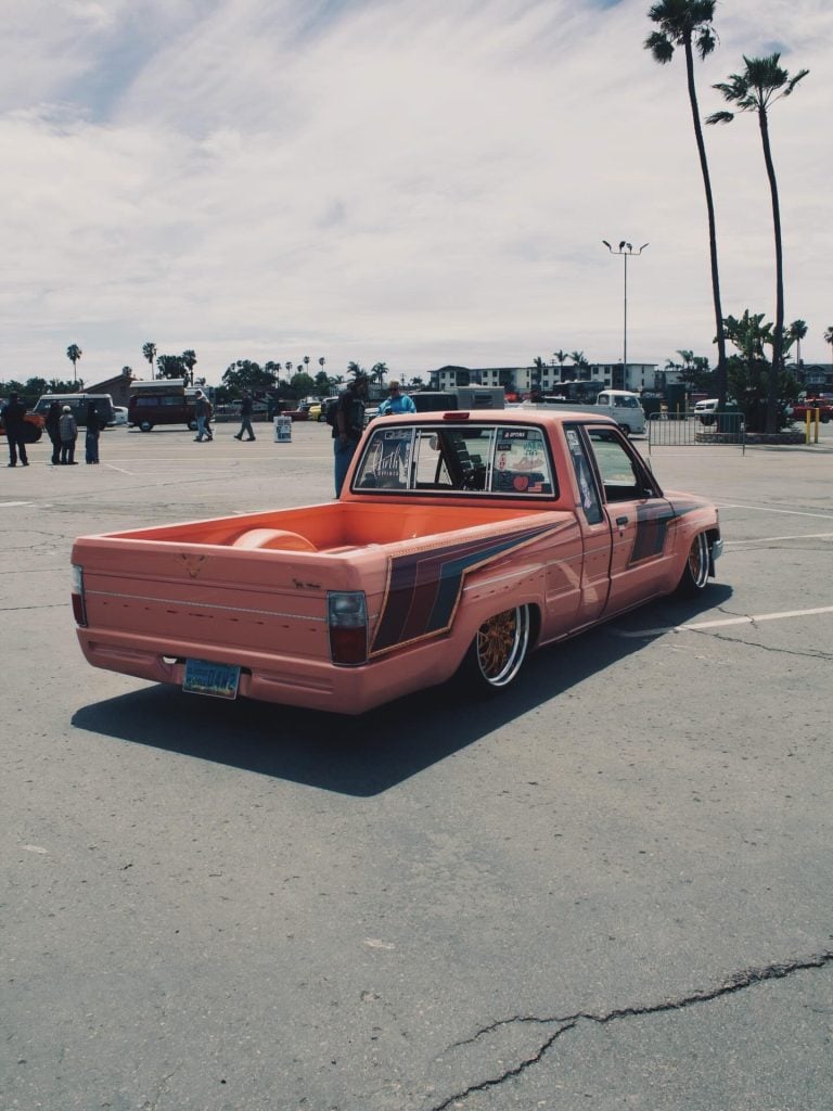 Rear three-quarter view of a pink Toyota pickup showing its side graphics and Klutch K3020 rear wheel