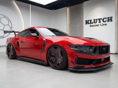 AI-generated visualization of a red Ford Mustang with black and red Golden Goal wheels, viewed from the front quarter