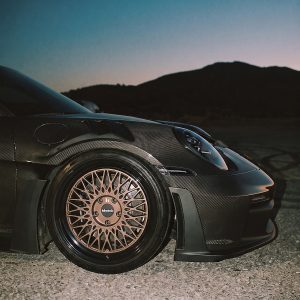 Close-up of a bronze-toned Klutch mesh front wheel beneath the carbon-fiber fender of a Porsche 911