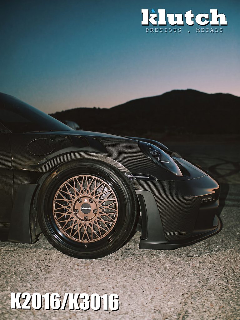 Close-up of a bronze-toned Klutch mesh front wheel beneath the carbon-fiber fender of a Porsche 911